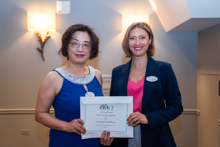 Two ELC staff members stand next to each other holding a certificate from the Barrington Area Community Foundation.